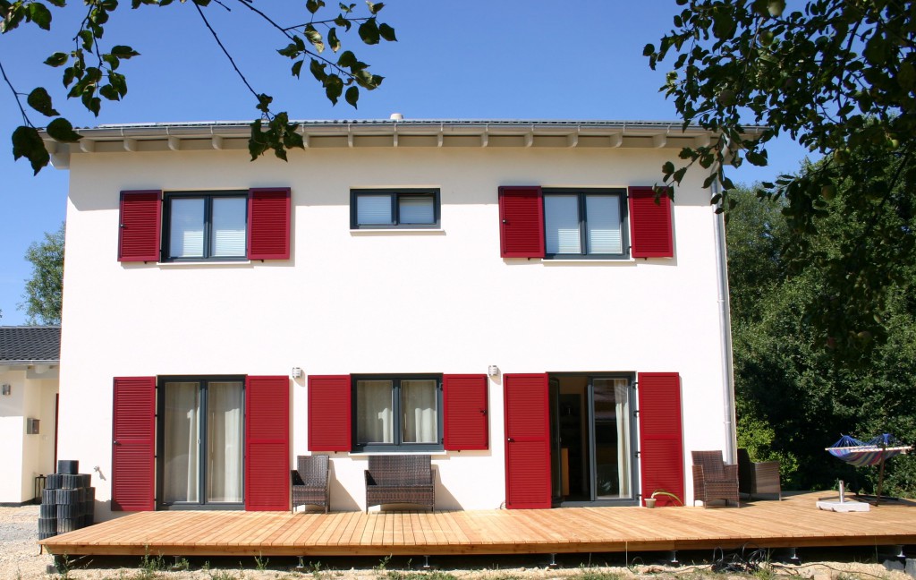 Das Einfamilienhaus mit roten Fensterläden und Terrasse.